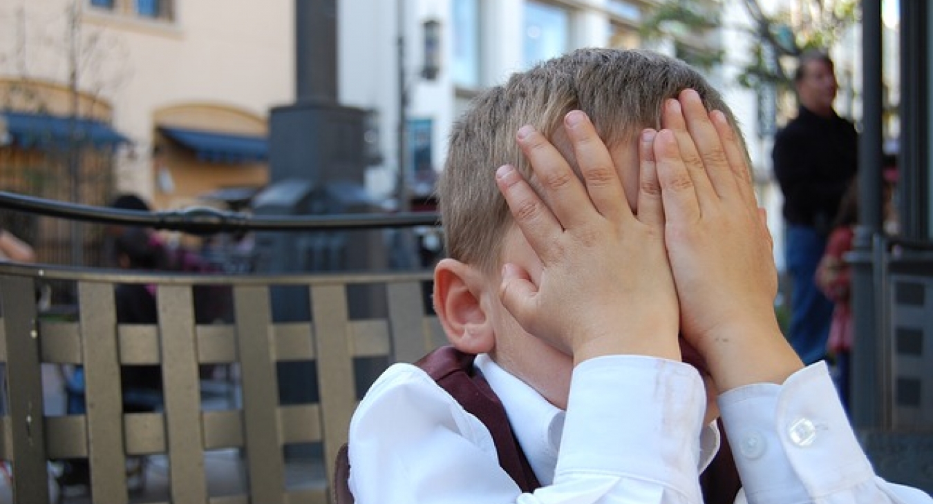 Boy with hands over face.