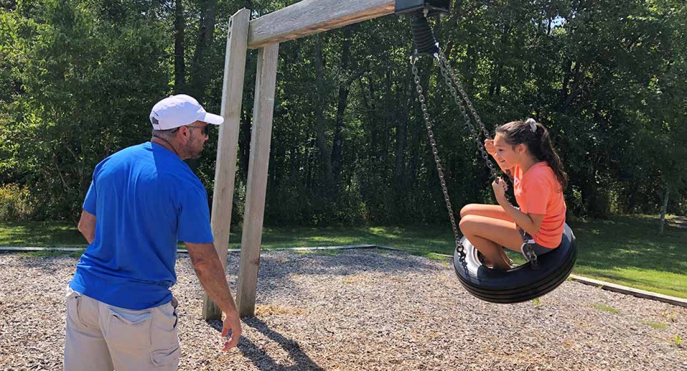Father pushing daughter on tire swing