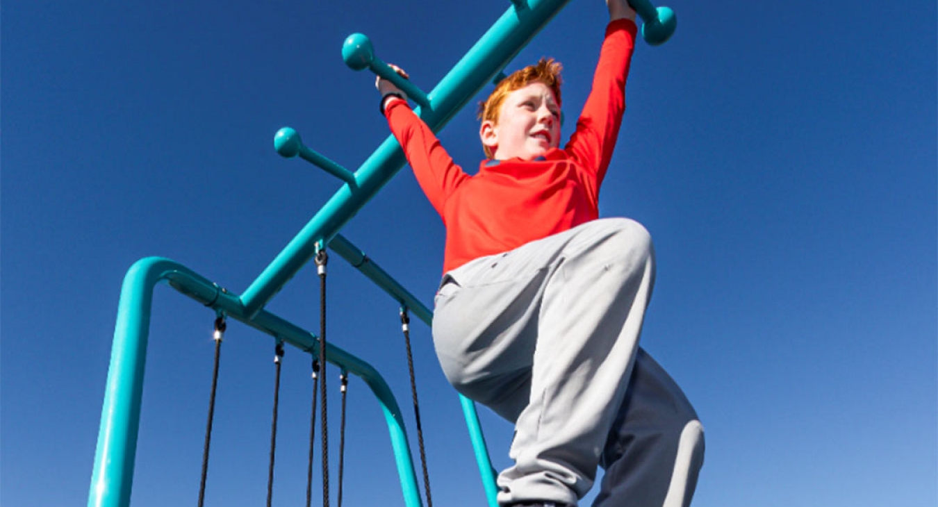 red headed boy crossing the monkey bars